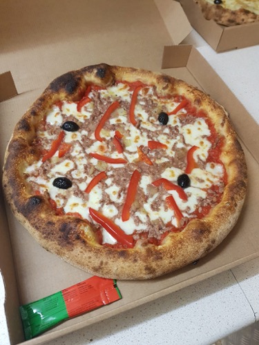Pizza garnie, aux bords dorés, prête à emporter.