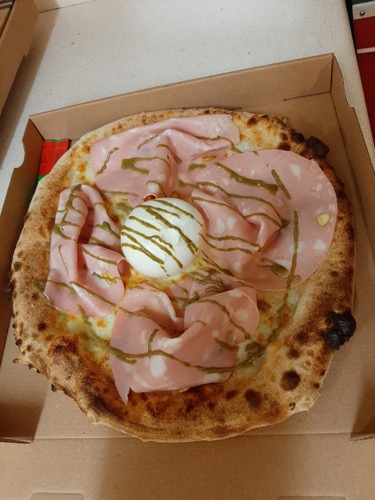 Pizza garnie de fines tranches et d'une boule de fromage au centre.