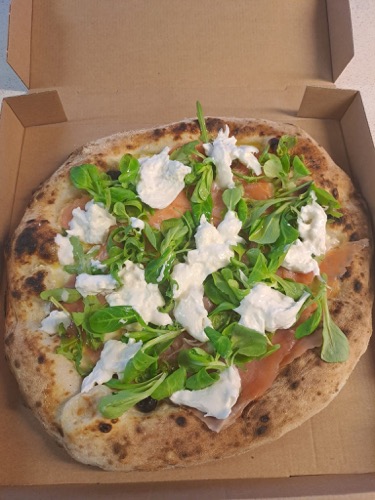 Pizza garnie de verdure et de morceaux de fromage blanc.