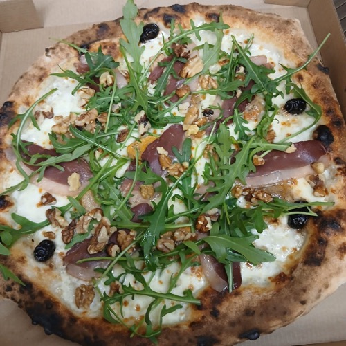Pizza garnie de roquette, de fromage et d'olives.